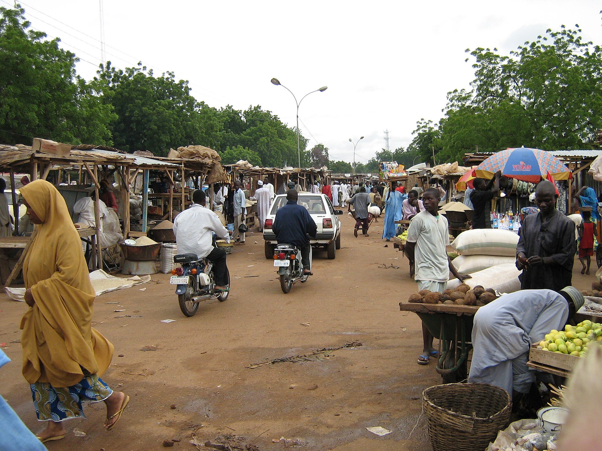 Market street in Sokoto with stalls, shoppers and motorcycles